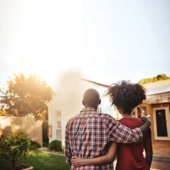 Rear view shot of a young couple admiring their new house outside
